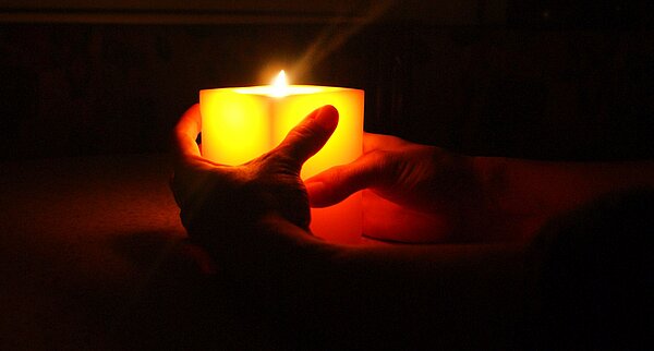 leuchtende Kerze in Händen gehalten