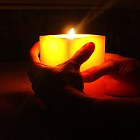 leuchtende Kerze in Händen gehalten