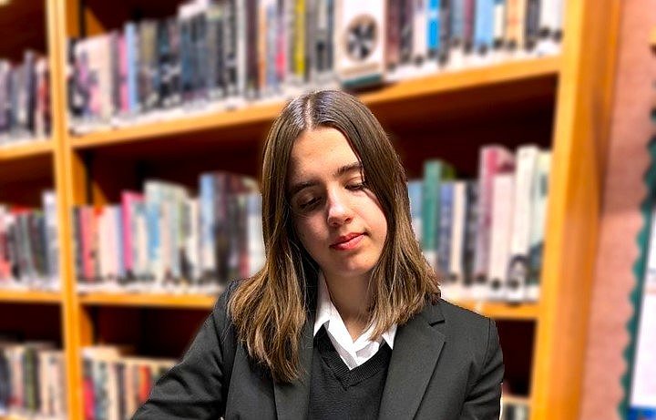 Carla Schadow liest in der Bibliothek aus einem dicken Buch.