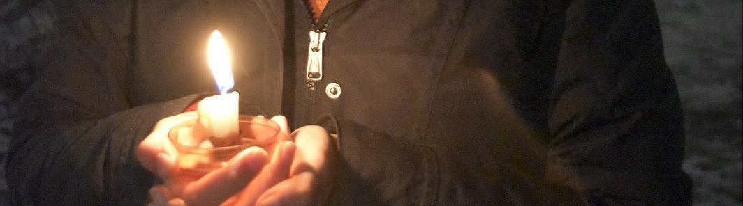 Brennende Kerze in der Hand bei Dunkelheit