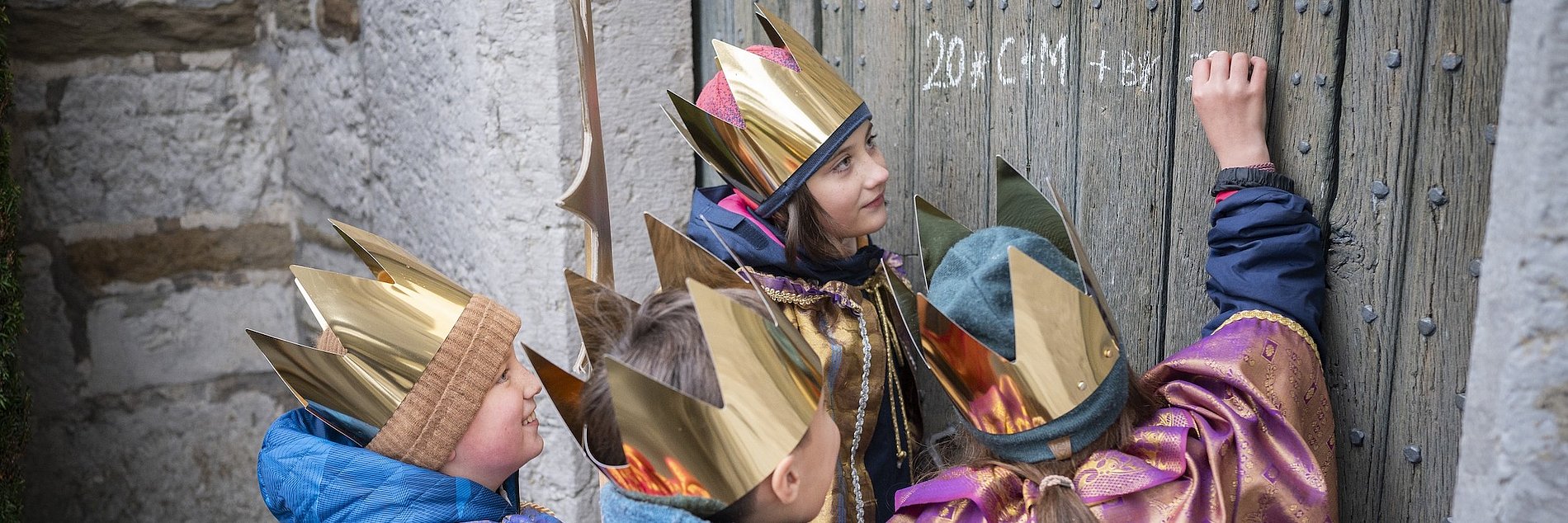 Sternsingergruppe schreibt den Segen an die Tür