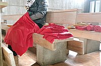 Gottesdienstbesucherin mit Decke über den Knien.