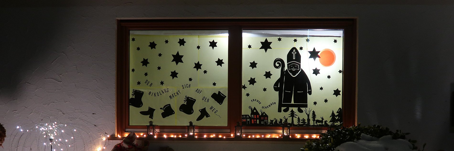 Mit dem Nikolaus und Weihnachtssymbolen beklebtes Adventsfenster.