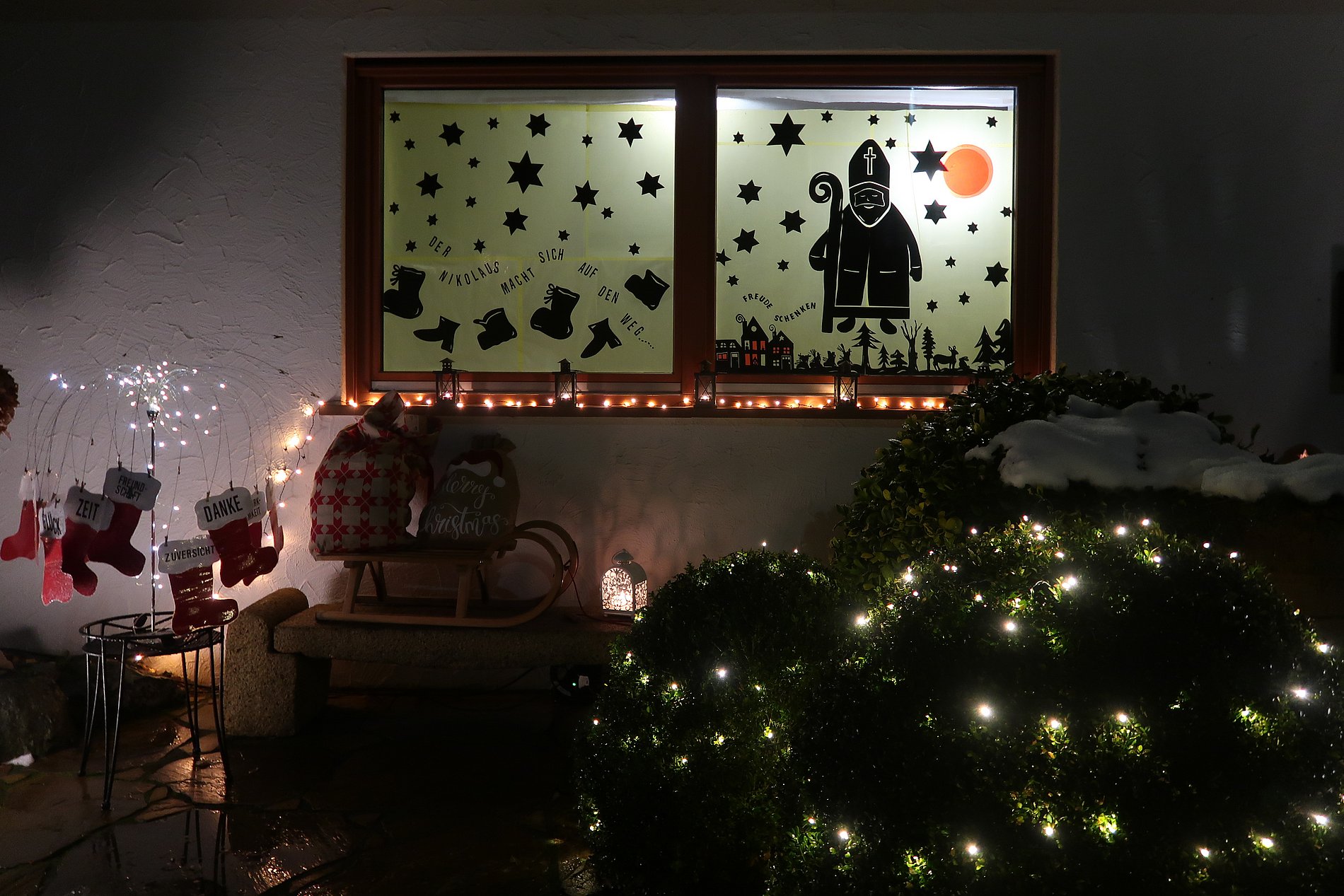 Mit dem Nikolaus und Weihnachtssymbolen beklebtes Adventsfenster.