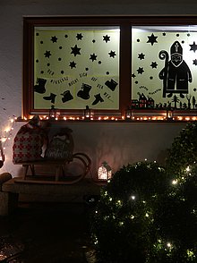 Mit dem Nikolaus und Weihnachtssymbolen beklebtes Adventsfenster.