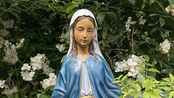 Maria als Figur mit Büschen im Hintergrund