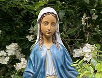 Maria als Figur mit Büschen im Hintergrund