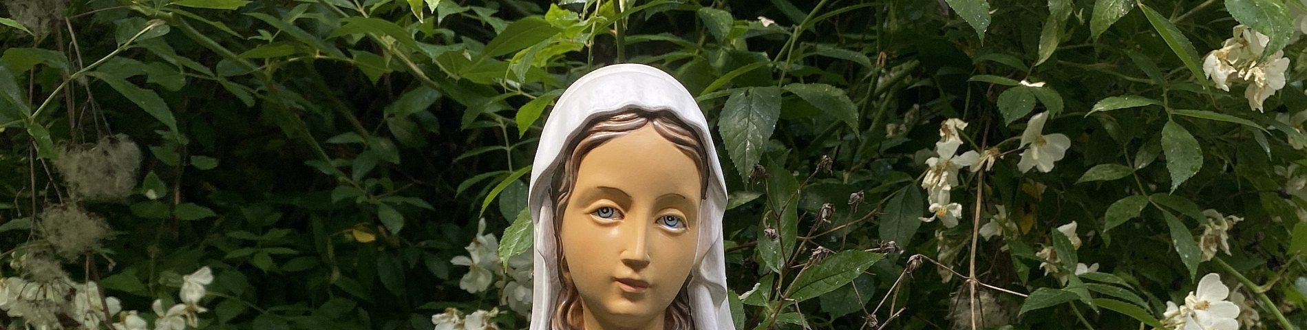 Maria als Figur mit Büschen im Hintergrund