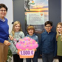 Die Erstkommunionkinder Maya, Diego, Konrad und Isabella (von rechts) überreichen Dorothea Ahlers (links) den großen Spendenmuffin.  