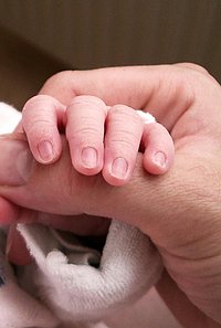 Babyhand hält den Daumen der Mutter