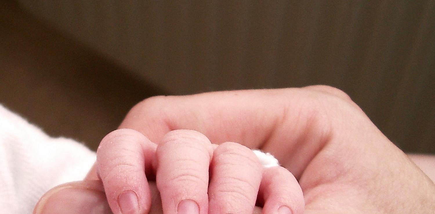 Babyhand hält den Daumen der Mutter