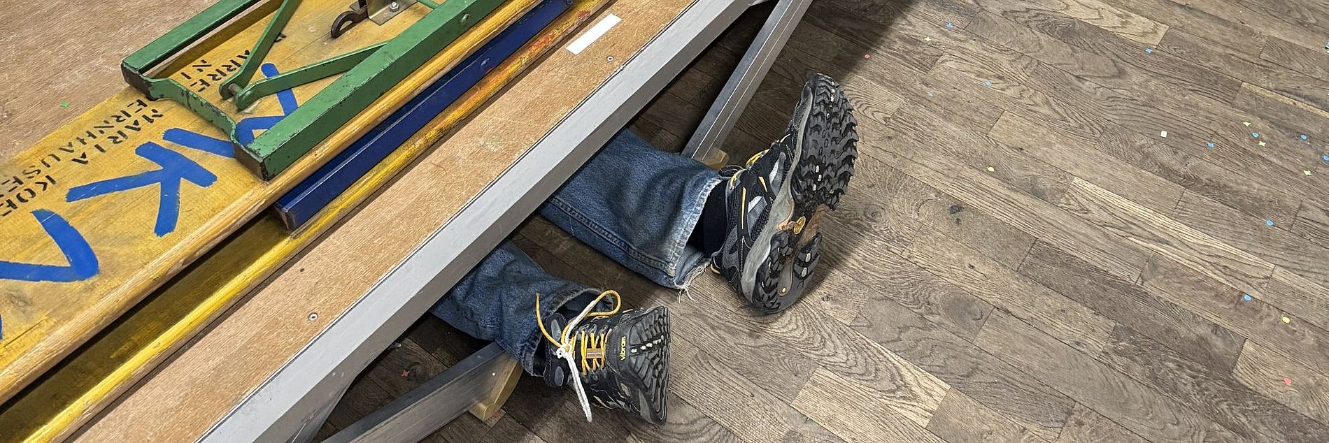 Ein Helfer liegt unter der abzubauenden Tribüne und schraubt. 