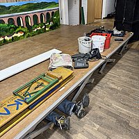 Ein Helfer liegt unter der abzubauenden Tribüne und schraubt. 