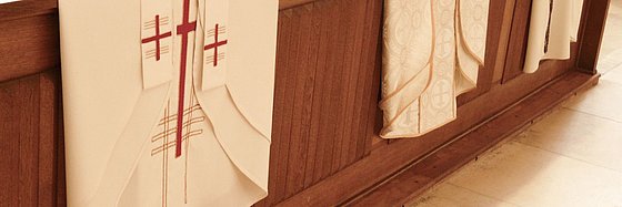 Priestergewänder die über einer Kirchenbank liegen