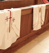 Priestergewänder die über einer Kirchenbank liegen