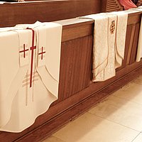 Priestergewänder die über einer Kirchenbank liegen