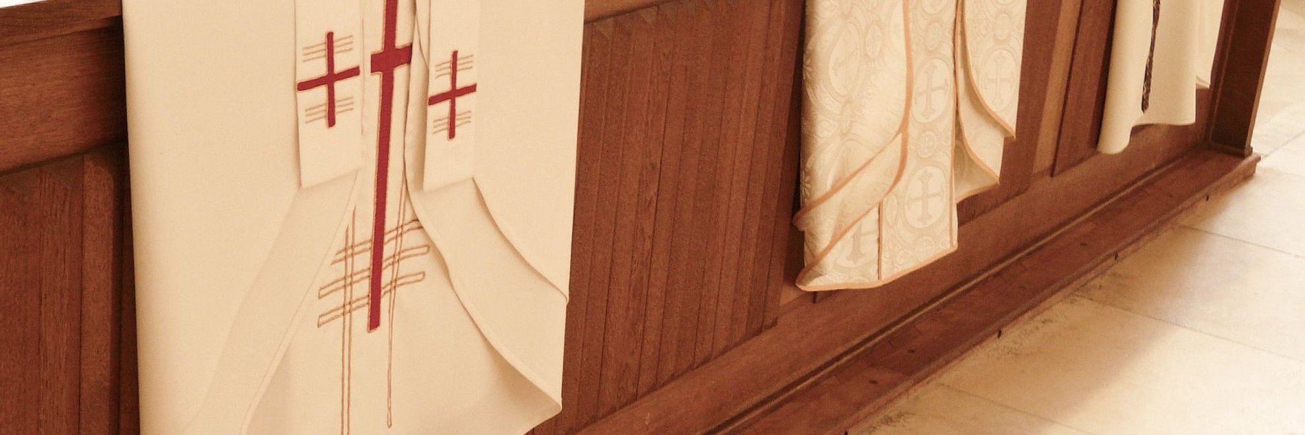 Priestergewänder die über einer Kirchenbank liegen