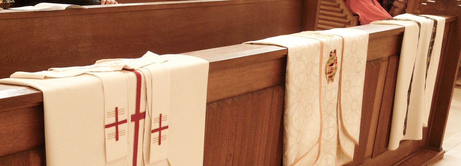 Priestergewänder die über einer Kirchenbank liegen